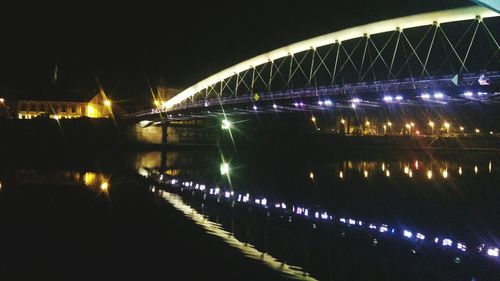 Illuminated bridge over river at night