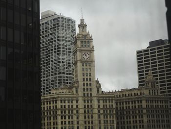 Low angle view of skyscrapers against cloudy sky