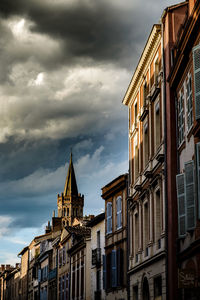 Low angle view of buildings against cloudy sky