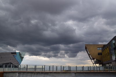 View of city by sea against storm clouds