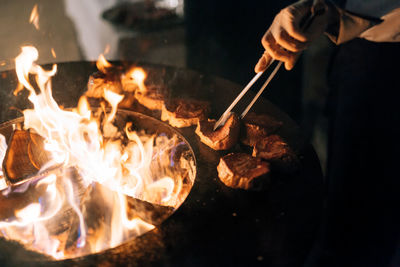 Midsection of person preparing burning candles on barbecue grill