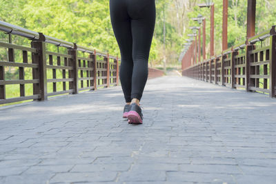 Low section of woman standing on footbridge