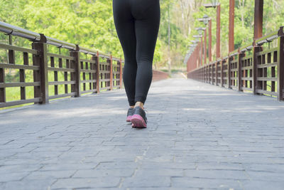 Low section of woman jogging on footpath at park