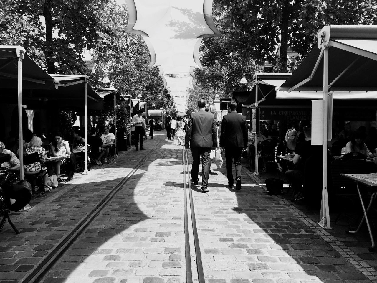 walking, the way forward, men, tree, street, city, person, lifestyles, building exterior, rear view, city life, full length, built structure, transportation, architecture, leisure activity, sidewalk, road, footpath