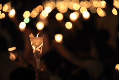 Close-up of hand holding illuminated lights at night