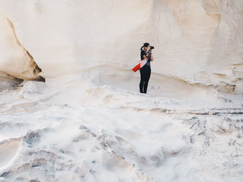 Full length portrait of woman photographing on rock