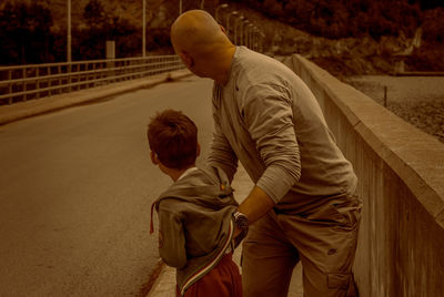 Man holding boy on bridge