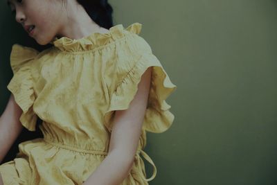 Midsection of girl sitting against wall