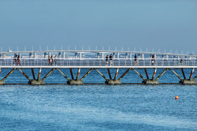 Bridge over sea against clear blue sky