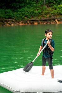 A young child is wearing life jackets paddling on an inflatable boat in kenyir lake, malaysia.