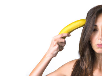 Portrait of woman holding banana against white background