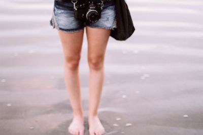 Low section of woman standing on beach