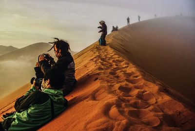 People photographing on mountain against sky