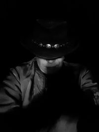 Portrait of man wearing hat against black background