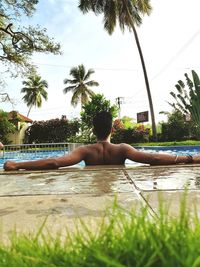 Man relaxing in swimming pool against sky