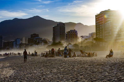 People on beach against buildings in city