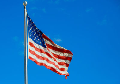 Low angle view of flag against blue sky