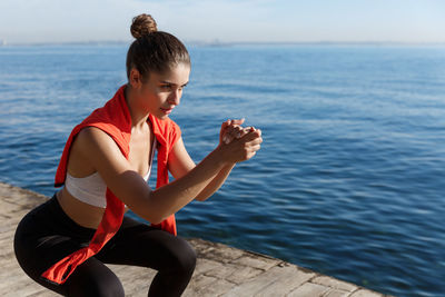 Woman exercising on pier near sea