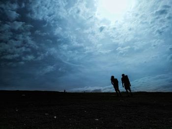 Silhouette men standing against sky