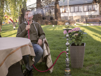 Portrait of young man smoking hookah in garden