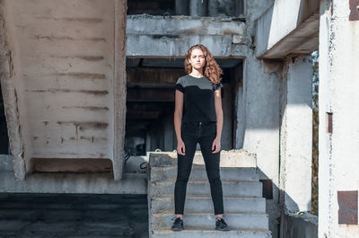 Cute teenage girl with curly hair standing on stairs. abandoned building, unfinished construction.