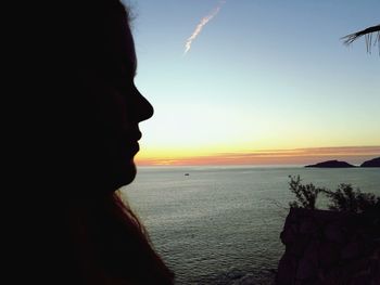 Portrait of woman looking at sea against sky during sunset