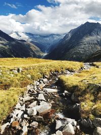 Scenic view of stream by mountains against sky