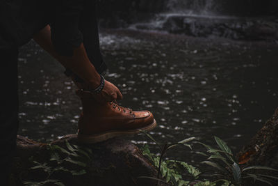 Low section of man wearing shoes at forest