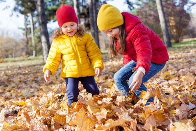 Sisters playing with autumn leaves in park
