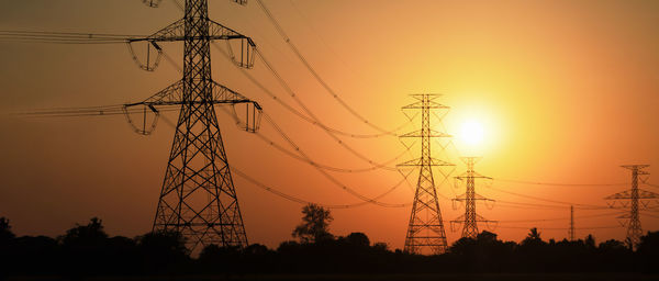 Electricity transmission towers in farmland at sunset, technology and communication