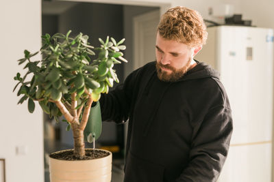 Side view of young man holding potted plant