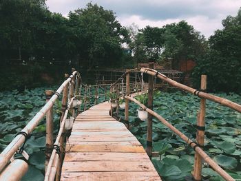 Footbridge over lake against sky