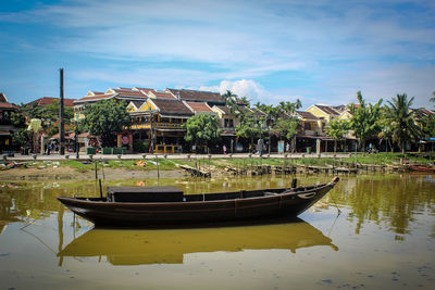 Boats on lake by building against sky