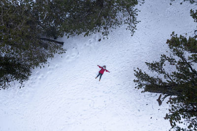 Drone aerial of woman wearing warm clothing lie down at snow in winter. troodos cyprus