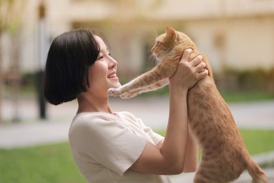 Side view of woman with cat against blurred background