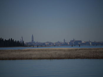 Scenic view of river by buildings against clear sky