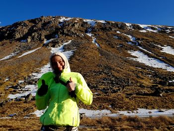 Portrait of woman gesturing thumbs up sign against mountains