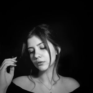 Close-up portrait of a beautiful young woman over black background