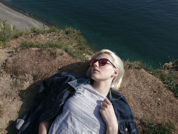 High angle view of woman lying on rock formation by sea