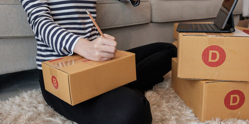 Midsection of woman holding umbrella in box