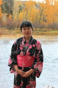 Portrait of woman in kimono standing against lake