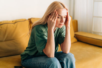 Young woman sitting on sofa at home