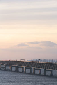 Bridge over sea against sky during sunset