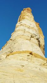 Low angle view of rock formation against clear blue sky