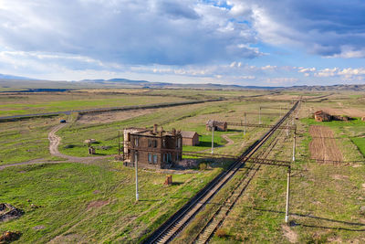 Railroad track amidst field against sky