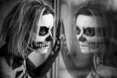 Close-up portrait of a woman in skeleton body paint with reflection on window