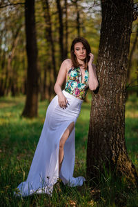 Full length of a young woman sitting on tree trunk