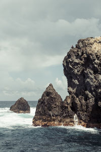 Rock formations by sea against sky