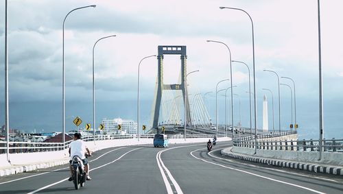 People riding bicycle on road against sky