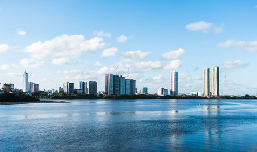 City at waterfront against cloudy sky